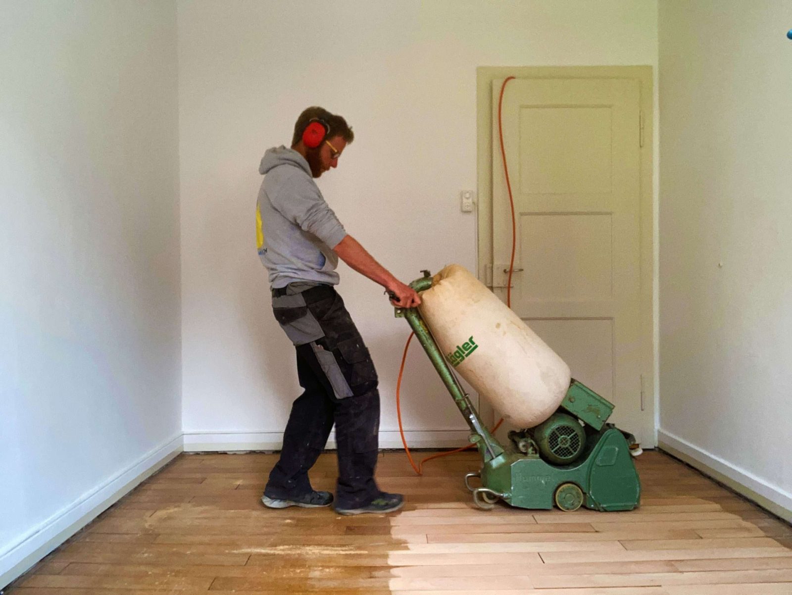 Parkett schleifen mit der Schleifmaschine in einem leeren Raum