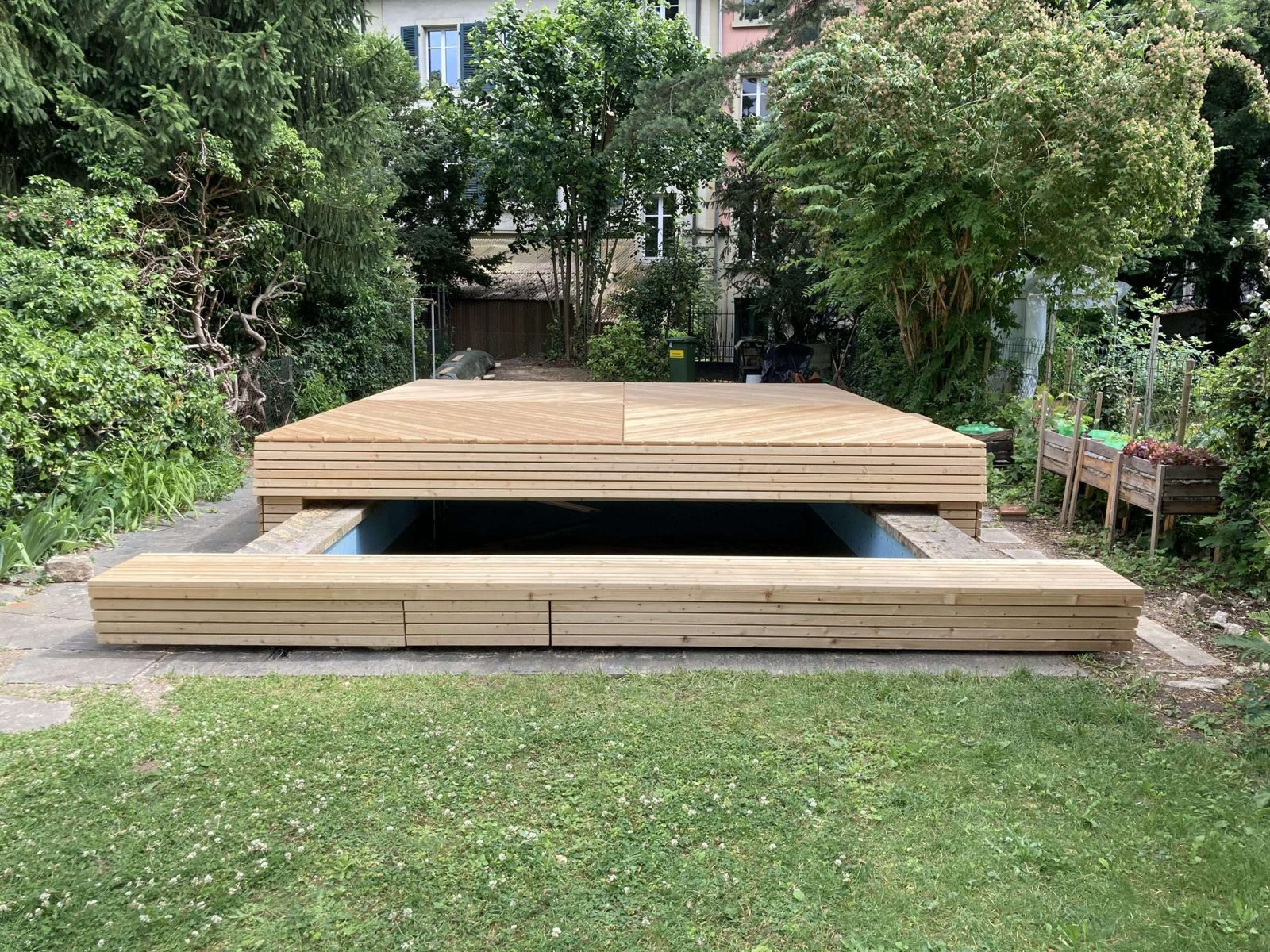 Holzabdeckung auf Rollen über einem Pool, mit Fernbedienung in der Hand
