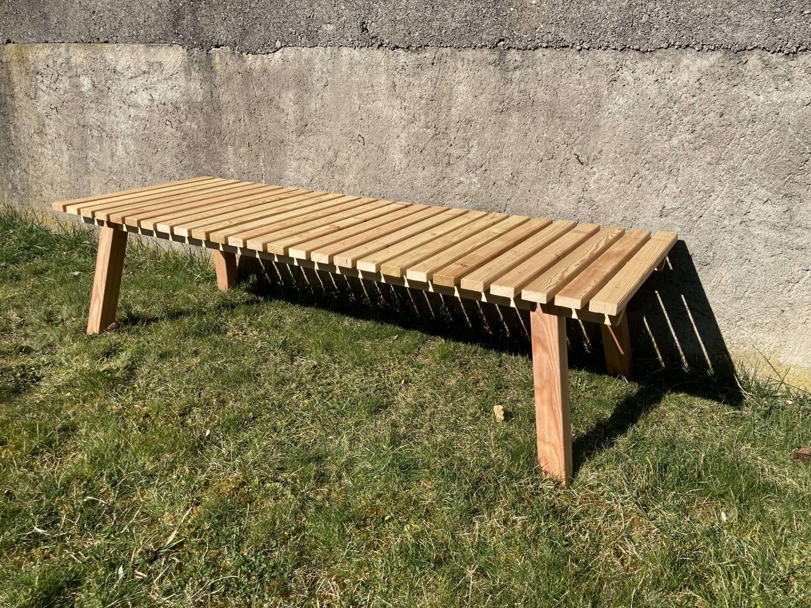 Sitzbank und Liege aus Holz auf einer Wiese